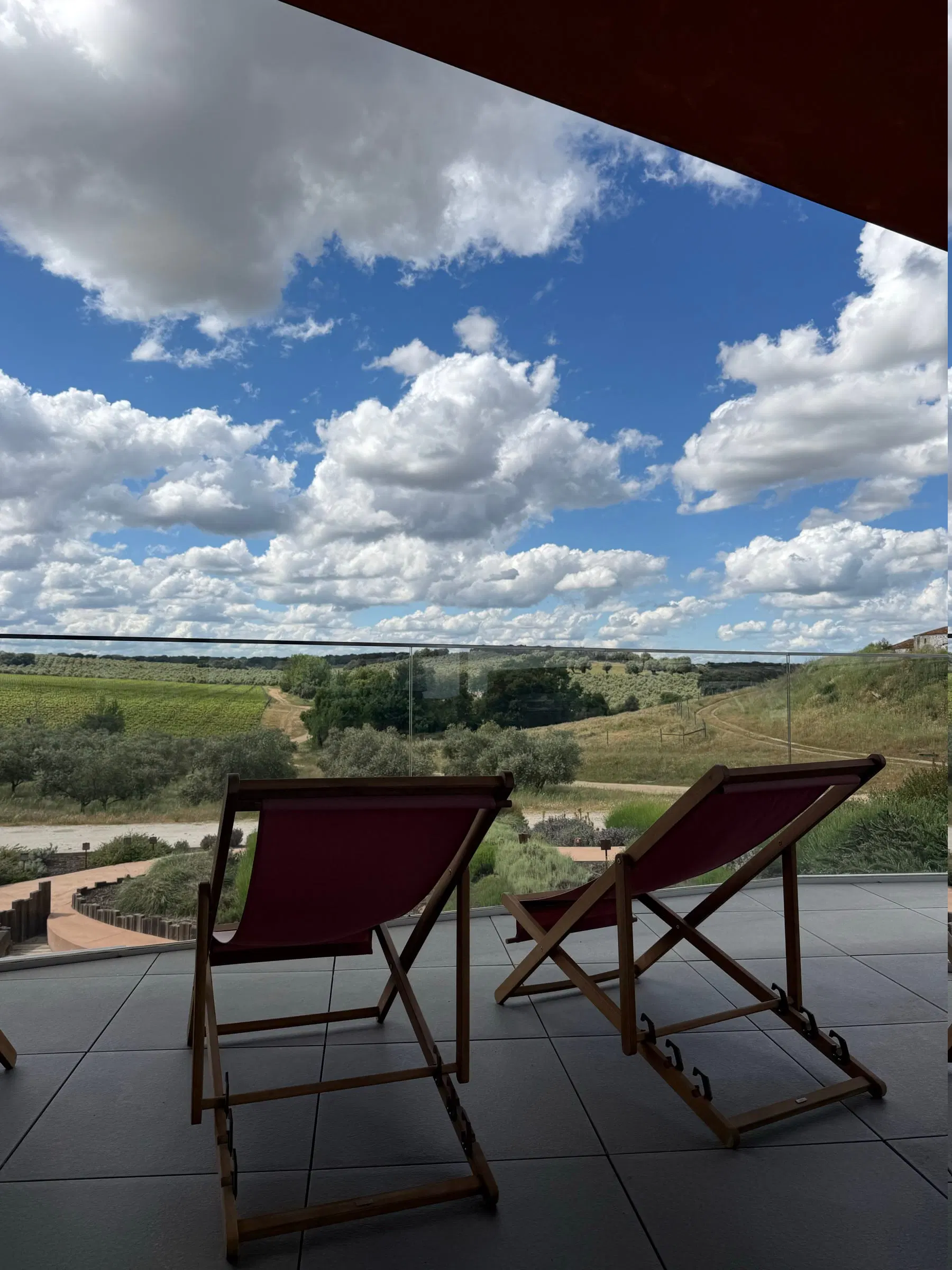 Duas espreguiçadeiras viradas para a planície, num terraço sobre a paisagem.