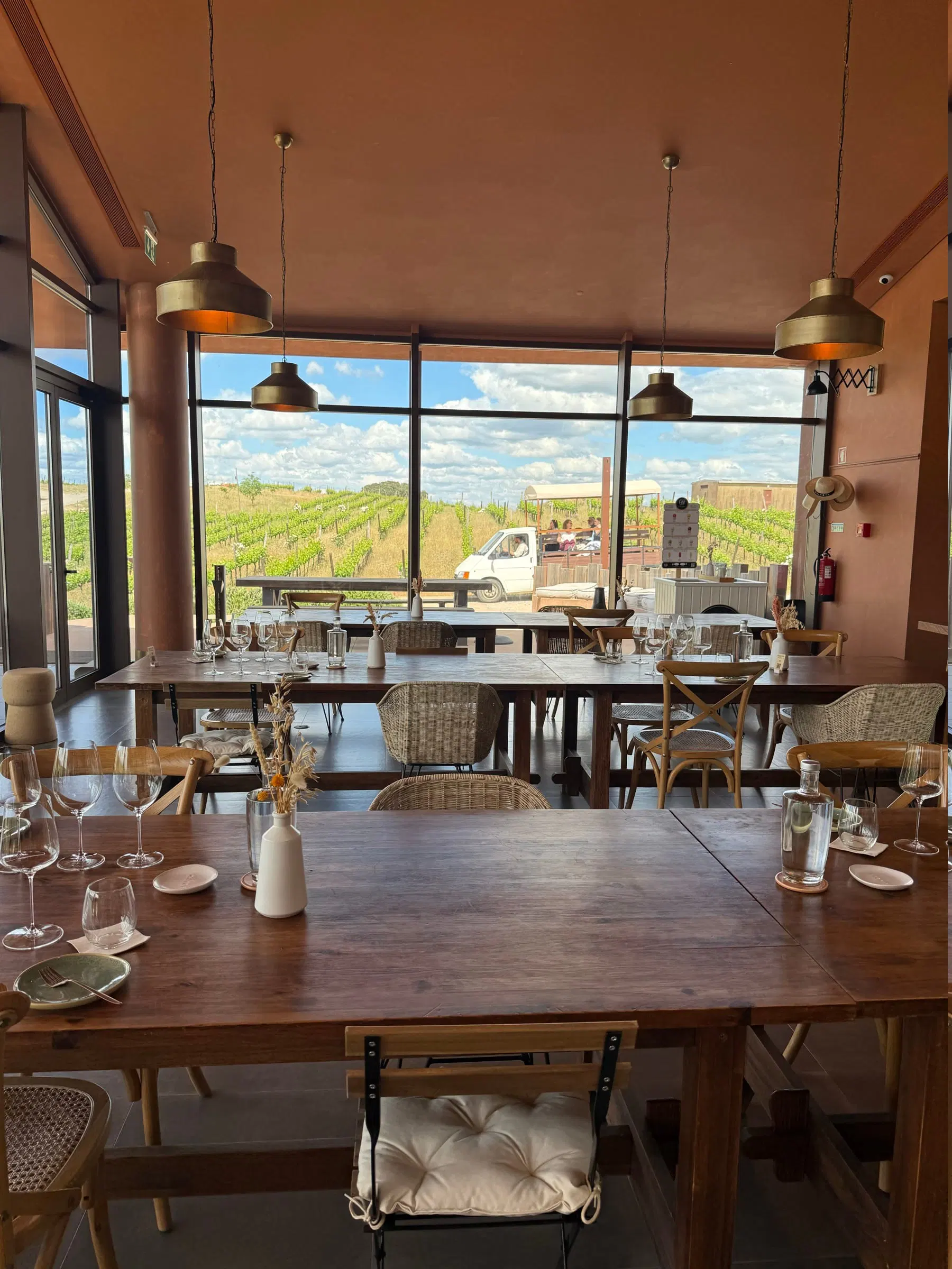 A sala de provas da Herdade da Mainova, com mesas de madeira e janela sobre a vinha.