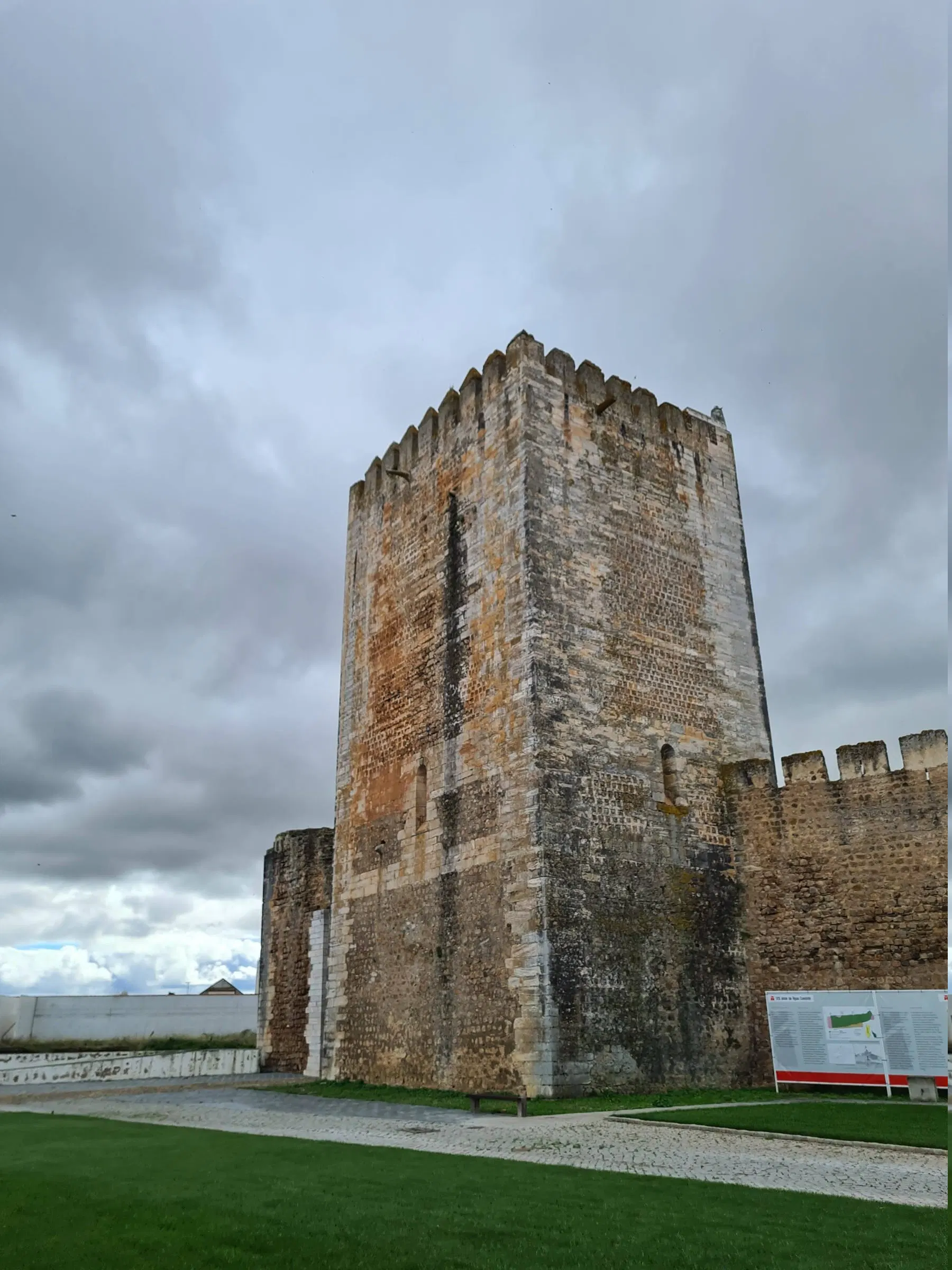 Torre de menagem do castelo de Moura, quadrada e ameada, contra céu carregado.