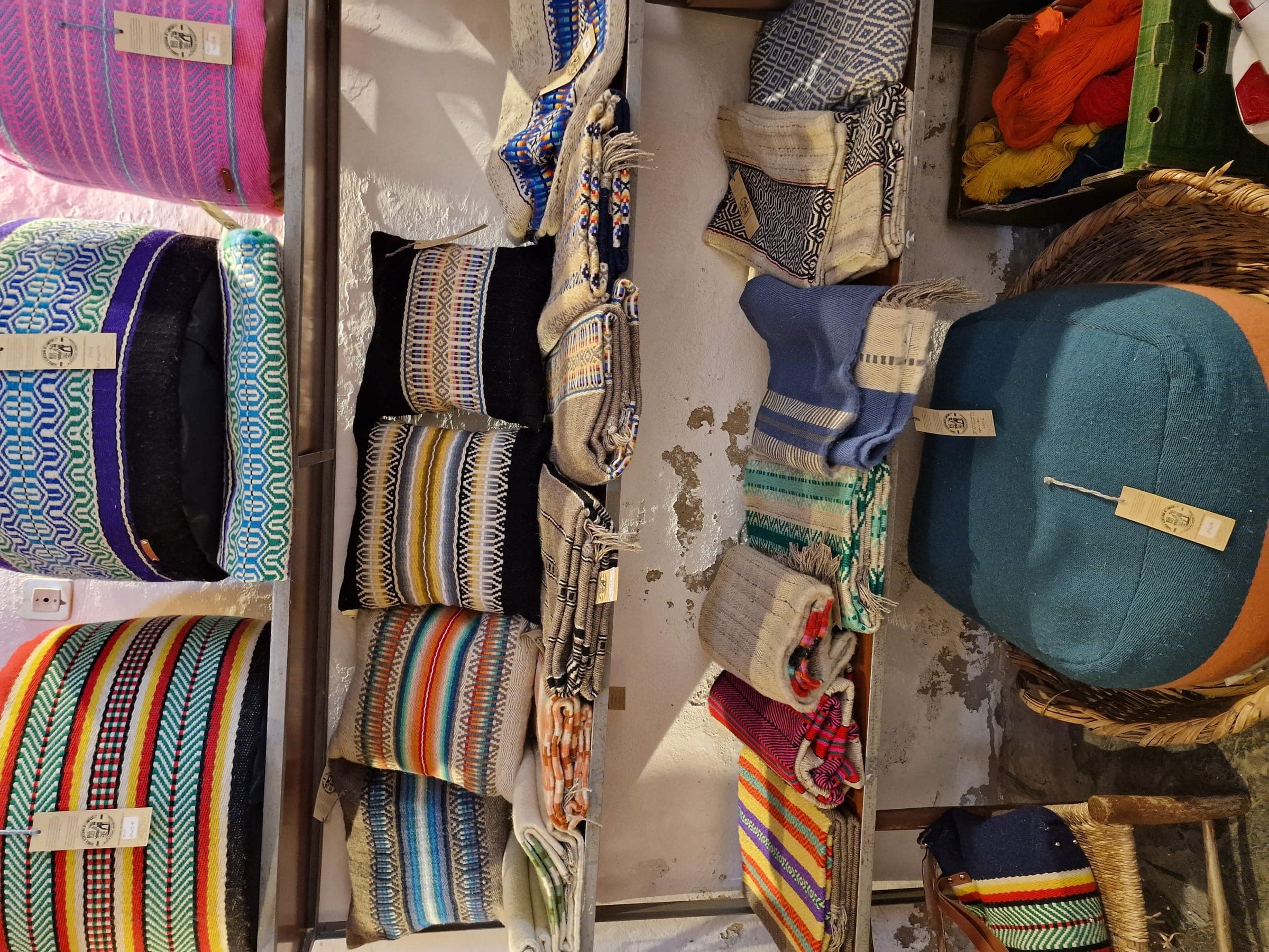 Mantas e almofadas de tear às riscas, empilhadas numa loja.