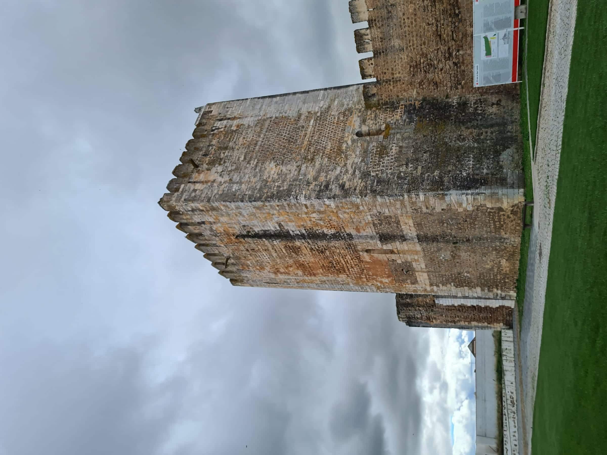 Torre de menagem do castelo de Moura, quadrada e ameada, contra céu carregado.