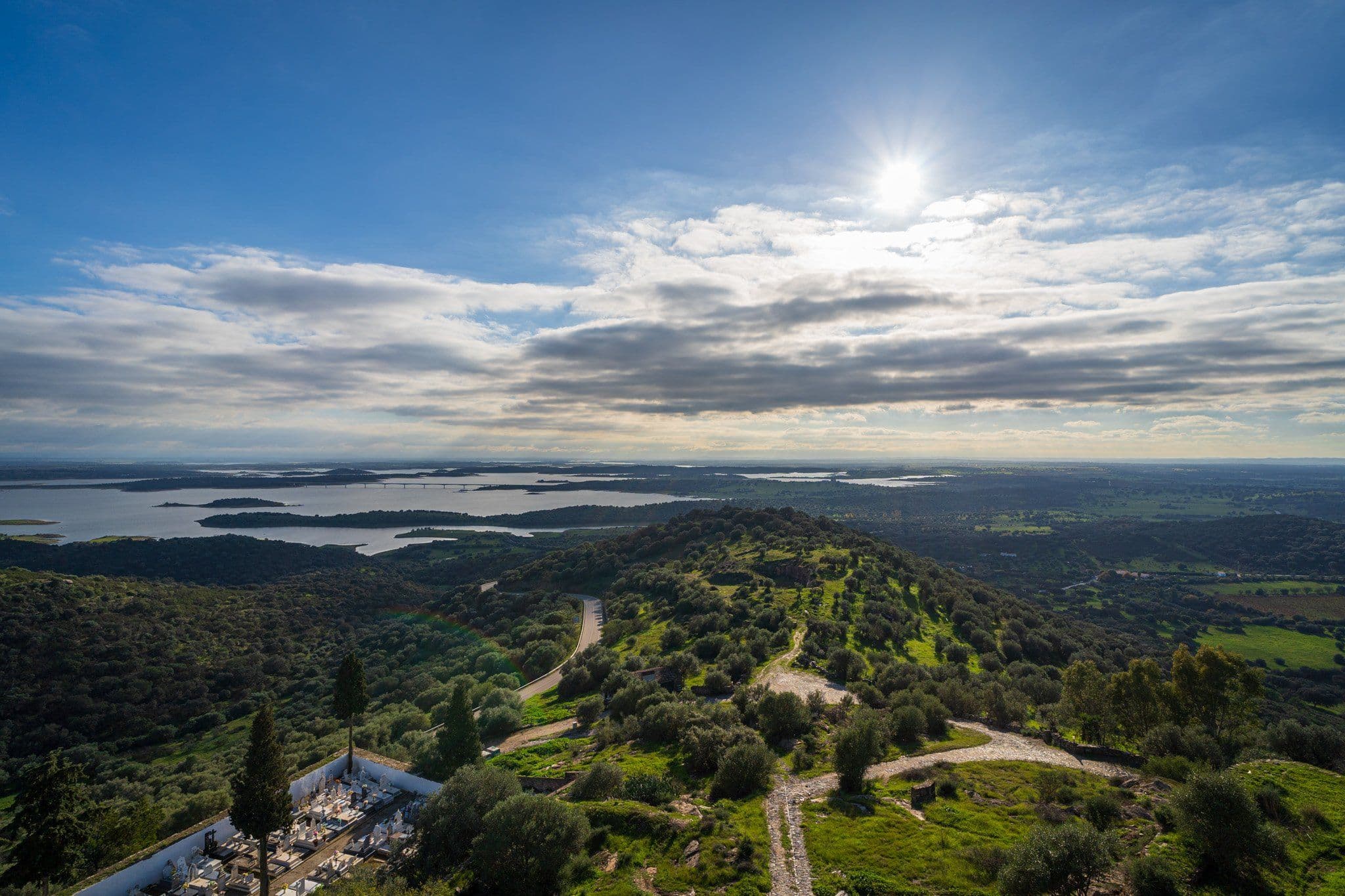 Wide view over Lake Alqueva from the hill at Monsaraz, the reservoir's islands in the distance and the green Alentejo plain in front.